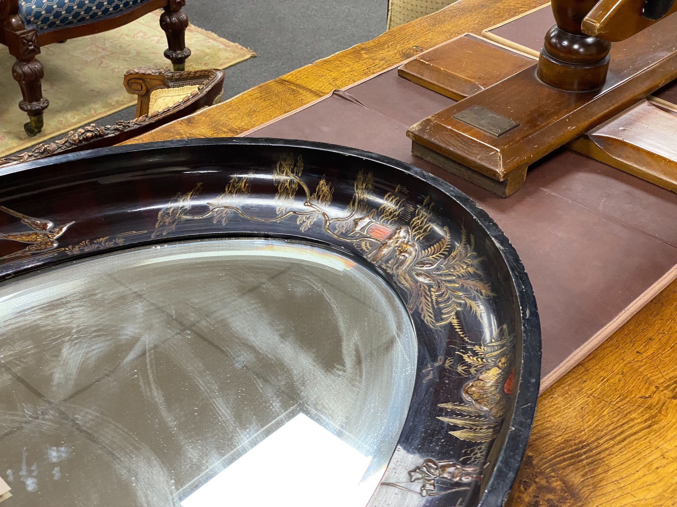 An early 20th century oval chinoiserie lacquered oval wall mirror, width 117cm, height 78cm